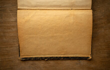 A Photograph Of An Old Yellowed Leaf In A Book On A Wooden Table. Antique Sheet Of Paper In Vintage Processing.
