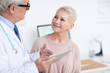 © Mediaphotos - Smiling healthy senior female patient with short hair listening to doctor who giving treatment advice