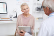 © Mediaphotos - Over shoulder view of elderly doctor using tablet while showing tests results to senior patient at appointment