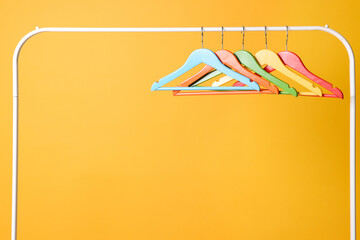 Sticker - Bright clothes hangers on metal rack against yellow background