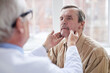 © Mediaphotos - Over shoulder view of doctor checking lumps on neck of aged male patient with mustache at appointment