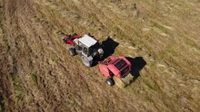The Tractor With The Device Collects Hay In The Field And Packs It Into Bales, The Tractor Makes Hay Bales, Drone View