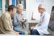 © Mediaphotos - Mature blond-haired woman looking at pill bottles and discussing medicine plan with doctor while her husband touching her shoulder and giving support