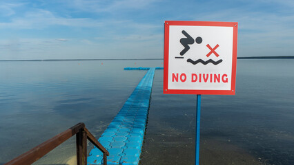 No Diving sign at beach, lake Naroch, Belarus. Warning sign of shallow water. Warning notice sign do not jump in water.