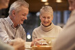 © Mediaphotos - Cheerful modern seniors in casual outfits sitting in cafe and using tablet while discussing social media accounts