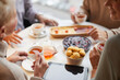 © Mediaphotos - Over shoulder view of seniors sitting at table with tablet and drinking tea with sweets while talking to each other