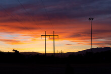 Vibrant Cloudy Sunset Landscape View Of Power Lines At Dusk In The Desert Southwest With Mountains In The Background