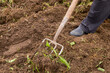 © Yulia - legs in boots with a pitchfork close-up, against the background of the ground. a man digs the ground with a pitchfork. garden work.Farmer man with garden tools