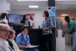 © DC Studio - Young man having casual conversation with hospital receptionist at front desk while nurse is checking appointment with young girl. Asian patient in clinic waiting room with diverse patients.