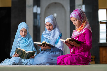 Wall Mural - A group of children girls reads the holy book Quran inside the mosque. 