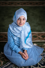 Wall Mural - A happy Religious Muslim girl wearing a modern fashion hijab praying inside the Mosque.