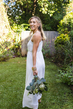 Vertical Image Of Happy Caucasian Woman In Wedding Dress Holding Flowers