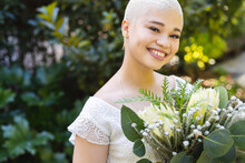 Image Of Happy Biracial Woman In Wedding Dress Holding Flowers