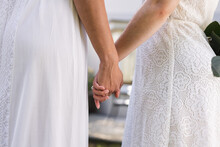 Image Of Midsection Of Diverse Lesbian Couple In Wedding Dresses Holding Hands