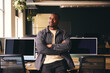 © Southworks - Smiling Young Black Male Standing In Office Looking Away From Camera With Arms Crossed