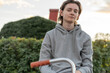 © FOLIO - Young man in hoodie sitting on bicycle