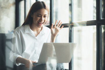 Asian businesswoman looking at laptop screen and remote video call with startup partner, she talks to her friend through program on laptop. Concept of using communication technology.