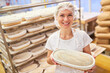 © Robert Kneschke - Junge Frau als Bäcker Lehrling zeigt stolz Backform mit Brot