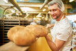 © Robert Kneschke - Bäcker Lehrling mit fertig gebackenem Brot auf Brotschaufel