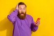 © deagreez - Photo of positive excited guy dressed purple sweater communicating modern gadget empty space isolated yellow color background