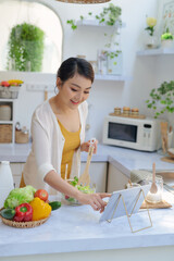 Wall Mural - Young asian woman  preparing vegetables for salad at her kitchen