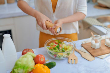 Wall Mural - Pretty young woman chef putting salt in a salad