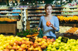 © Liubomir - woman picks chooses fruits vegetables on the counter in supermarket. Female housewife shopping in market standing near vegetable department store with a basket in hands. Examines apple