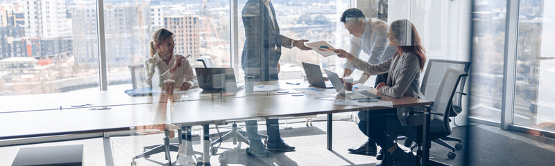 Wall Mural - Creative business people working on project in modern office with panoramic view. Teamwork concept