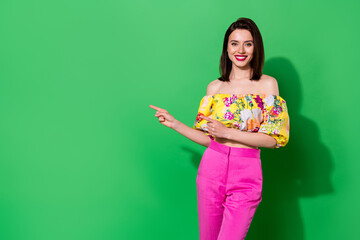 Wall Mural - portrait of positive lovely girl indicate fingers empty space proposition isolated on green color ba