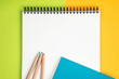 © wisoot - colored pencils placed on a school notebook on a yellow and green background spiral notebook on table