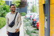 © Home-stock - A male client receives goes to receive a parcel in a self-service post terminal. Online store client.
