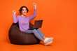canvas print picture Full length portrait of delighted positive girl sitting comfy bag raise fists isolated on orange color background