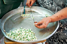A Street Seller Is Making  A JAsmin Necklace In Thailans