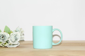 Sticker - Blue mug and flowers on a wooden table against a white wall