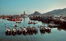 Fishing Boats In The Harbor Against The Hills And Blue Sky. Dalian, China.