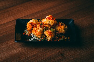 Sticker - High angle shot of an Asian chicken dish with a red sauce and chopped scallions on a black plate