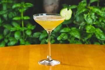 Poster - Orange-colored cocktail with cucumber dressing on a wooden table