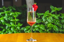 Serving Of Champagne With A Strawberry On A Wooden Table