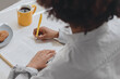 © Cavan Images - A woman writes her thoughts in a diary at breakfast .