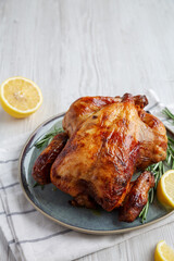 Wall Mural - Homemade Lemon and Herb Rotisserie Chicken on a Plate, side view. Copy space.