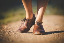 Legs Of A Young Girl With Brown Shoes Walking On A Pathway