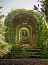 Vertical Shot Of Stony Arch Surrounded By Flowers And Leaves In Park Of Arundel Castle