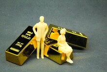 Small Men And Women With A Background Of Three 200g Gold Nuggets.