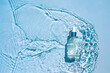 Moisturizing cosmetic product, serum in a transparent bottle with a dropper in water waves, blue background