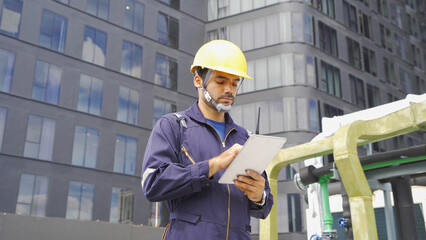 Wall Mural - An engineer man or worker, people working in industry factory, using a tablet technology device on rooftop building. System work machine. Condenser Water Supply pipe lines. Workshop site.