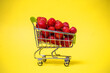 a supermarket cart full of red strawberries on a yellow background