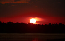 The Sun Goes Below The Horizon. Sunset Over The Forest. The Sun Hides Behind The Trees. Red Sunset And Bright Sun