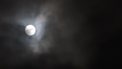 Wall Mural - night sky is illuminated by full moon shining through dark clouds which take over turning sky black.