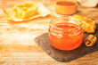 Glass jar with sweet honey and dipper on wooden table, closeup. Space for text