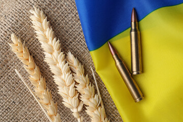 Wall Mural - Bullets, spikelets and national Ukrainian flag on burlap, flat lay